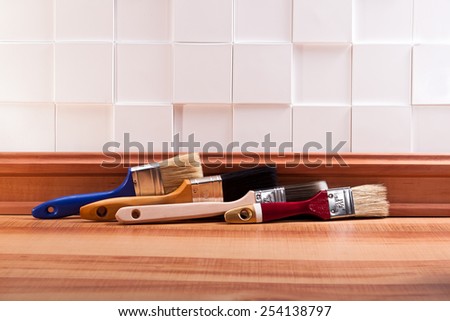 Paint brush on the parquet floor with a decorative wall