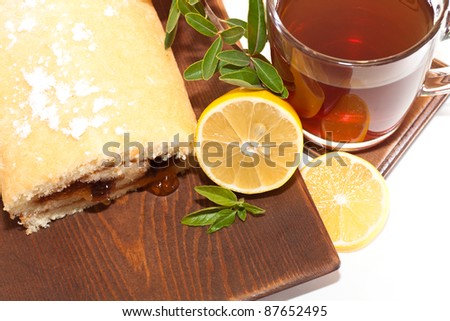 cake on a wooden platter with lemon and a glass of tea