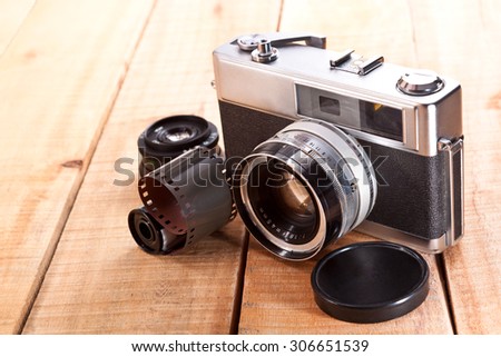 Old camera, film, lens on a wooden table
