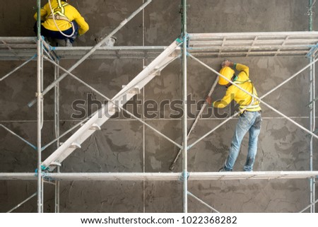 Construction worker plastering cement on concrete block wall