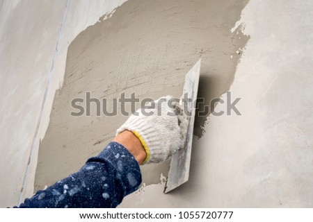 closeup hand construction plastering wet cement on the loft wall