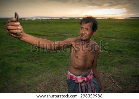 Dramatic Asian Man standing on green field during sunset