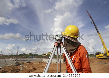 surveyor worker working with  equipment at factory construction site outdoors blue sky background