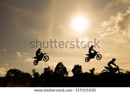 Blurred silhouette of motocross  rider jumping on the mountain in sunset