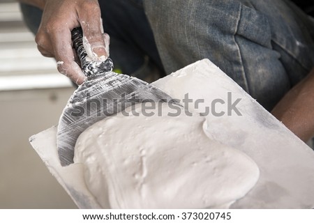 Hand worker spreading plaster with trowel to gypsum board and fi