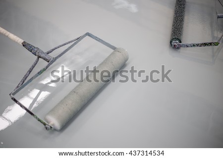 Builder worker use a roller paint epoxy at floor new factory
