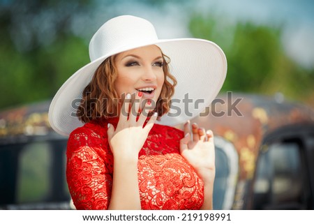 Beautiful woman in white hat expresses the joyful emotions. Female sexual appearance looks overlooking pine. Close up of a younger woman in a red dress and a white hat.