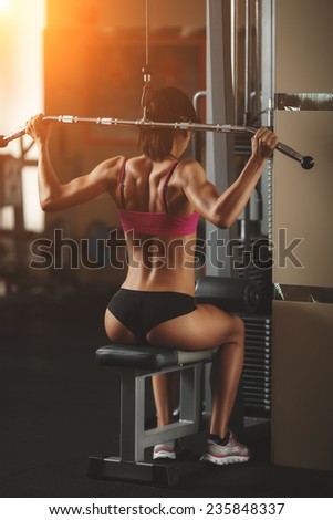 Body of a beautiful young girl in the fitness room rear view. Athletic young woman doing a fitness workout. Attractive fitness woman, trained female body, lifestyle portrait, caucasian model