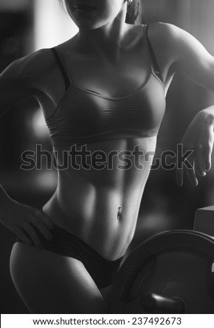Young strong woman black and white portrait. Brunette sexy fitness girl in sport wear with perfect body in the gym posing before training set. Attractive fitness woman, trained female body