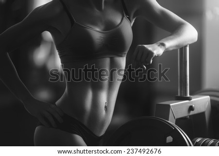 Young strong woman black and white portrait. Brunette sexy fitness girl in sport wear with perfect body in the gym posing before training set. Attractive fitness woman, trained female body