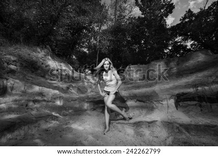 Black and white photo of a beautiful blonde, sexy appearance that posing in denim shorts and white T-shirt in the Canyon sandy