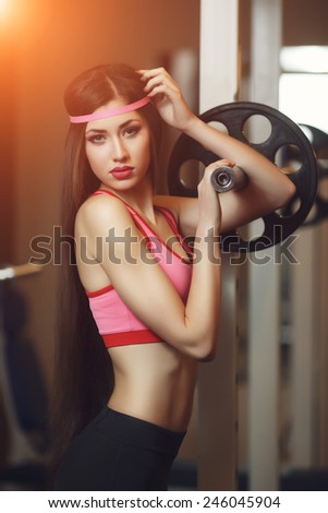 Sexy brunette with long hair and sporting appearance posing in the gym.