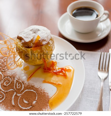 Baked apple with honey beautifully decorated white powdered sugar and a cup of coffee. Shallow depth of field.