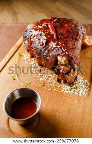 Baked meat with red chili pepper on wooden board closeup
