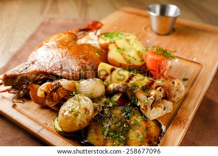 Roasted duck meat with vegetables and orange sauce on a wooden board closeup