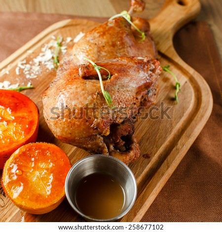Roasted duck meat with vegetables and orange sauce on a wooden board closeup