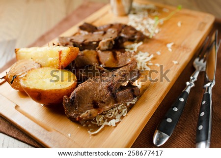 Baked meat with potatoes and onions on a wooden board
