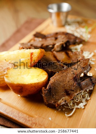 Baked meat with potatoes and onions on a wooden board