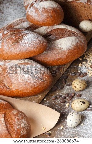 Variety of rye bread on a wooden background with flour, grain and quail eggs