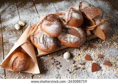 Variety of rye bread on a wooden background with flour, grain and quail eggs