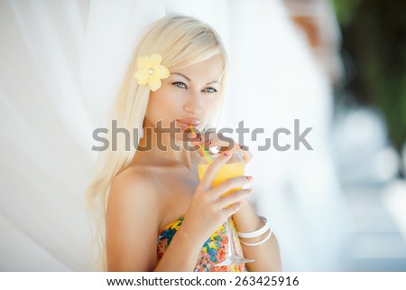 Sexy blonde with long straight hair and plump lips posing in a yellow suit in the sun, blue sky and white developing material