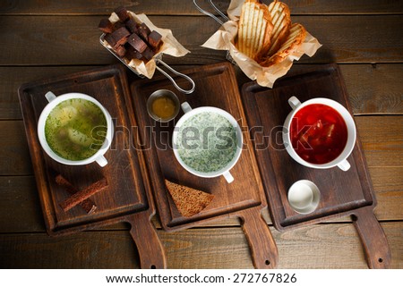 Three different traditional Ukrainian Russian cuisine, chicken broth with egg, okroshka and red borsch on wooden boards with rye and wheat bread, top view