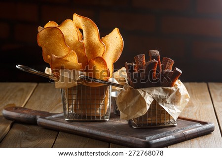 Appetizing fried golden brown croutons of rye and wheat bread in a metal basket on a brown wooden background, backlit, close-up