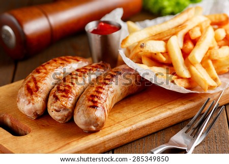 Close-up of fried sausages with fries on wooden table
