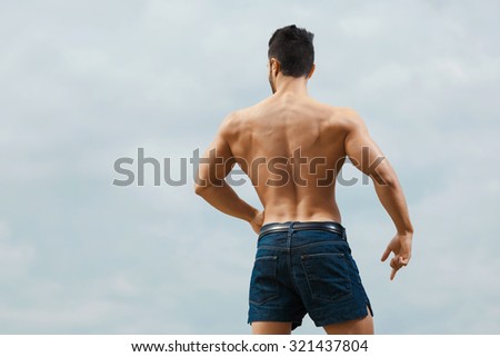 Muscular naked man from back on sky background