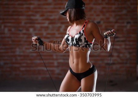 Beautiful fitness woman with the jump rope on the brick wall background. Healthy lifestyle, diet and fitness