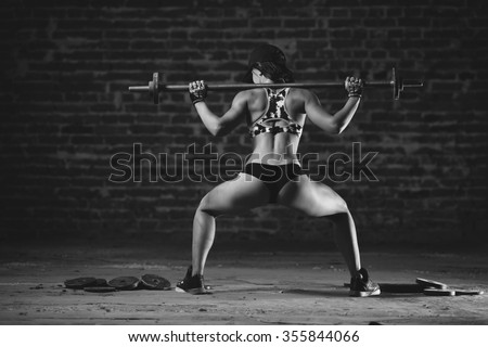 Beautiful sporty sexy woman doing squat workout in gym. Black and white photo