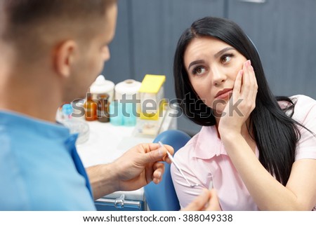 Girl patient goes to the dentist with a toothache in the dental office. Young woman holding the hand of a sick tooth