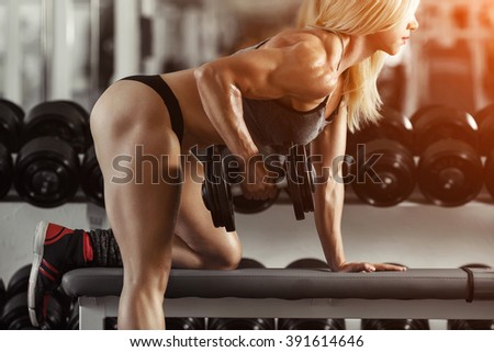 Classic bodybuilding. Muscular blonde fitness woman doing exercises in the gym. Fitness woman in the gym. Bodybuilder woman in the gym. Fitness woman with dumbbell.
