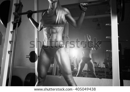 Fitness woman doing squats with the barbell at the gym. Smith Machine in the gym.  Fitness woman in the gym. Perfect fitness female figure. Fitness - concept of healthy lifestyle. Crossfit woman