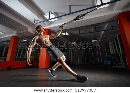 TRX training. Crossfit instructor at the gym doing TRX Excersise. Fitness man workout on the rings. Fitness man in the gym. Fitness style. Workout on rings. Sport and fitness. Crossfit workout