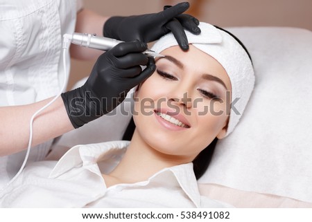 Permanent makeup. Permanent tattooing of eyebrows. Cosmetologist applying permanent make up on eyebrows- eyebrow tattoo
