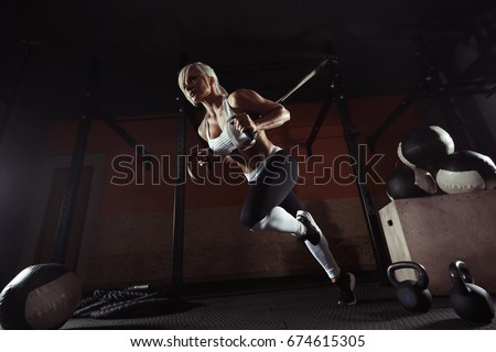 Fitness woman workout on the TRX in the gym. Fitness woman workout on the CrossFit. Fitness woman in the gym. Crossfit woman. Crossfit style. Training TRX straps. TRX gym