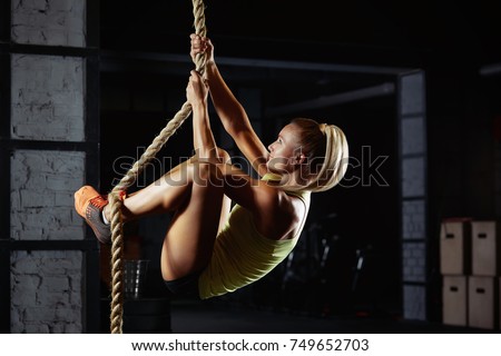 Shot of an attractive female crossfit athlete climbing a rope at the gym. Beautiful woman rope climbing at the crossfit box motivation positivity health concentration agility active living Battle rope