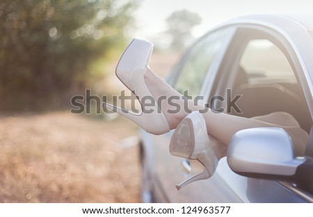 Sexy woman legs on high heels out the windows in car.