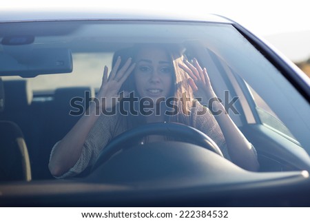 Young woman sitting scared in car.