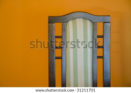 Part of chair on orange wall