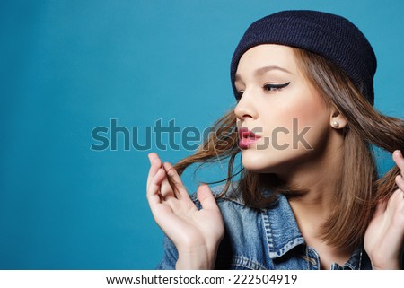 Closeup studio shot of pretty hipster teenage girl with beanie hat wearing jeans jacket looking at camera posing.