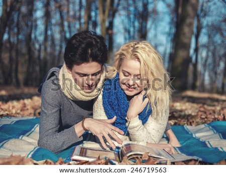 Happy couple lying in garden together reading a book or magazine on a sunny day