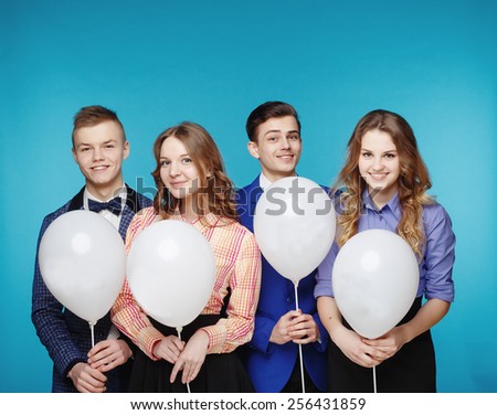 Group of smiling young people holding white balloons on blue background. Hipster style.