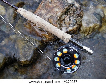Fishing tackle (fly rod and reel) on stones in a stream