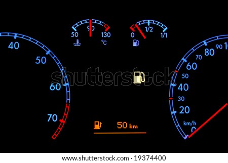 Car dashboard shows low fuel in the night