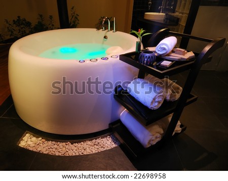 Stock photo bathroom with a modern jacuzzi whirlpool and towel trolley illuminated with different source of 22698958