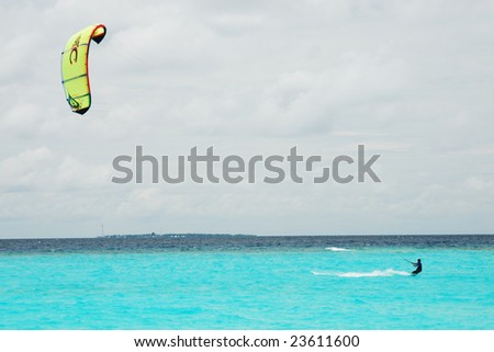 Kite Surfing. Kiteboarder with yellow kite over the cloudy sky.