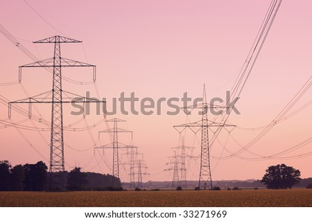Electric high tension transmission lines head into the horizon at dawn (tinted image).