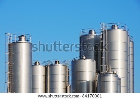 Storage tanks of dairy plant against blue sky.